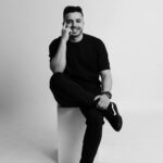 Home Black and white portrait of a smiling man sitting in a studio in São Paulo.